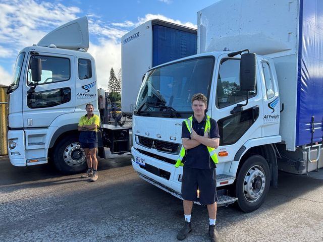 Two All Freight Carrying drivers standing with their trucks in the Yandina depot yard